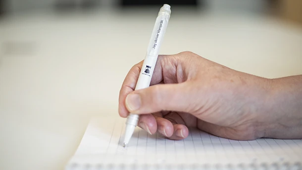 En hand med en penna med texten klarspråk.