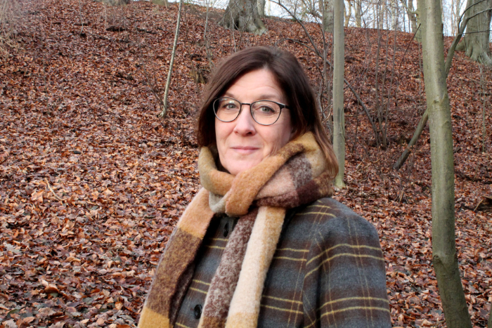 Kristina Lembke med halsduk i en skog om hösten.