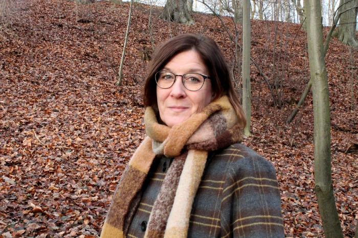 Kristina Lembke med halsduk i en skog om hösten.