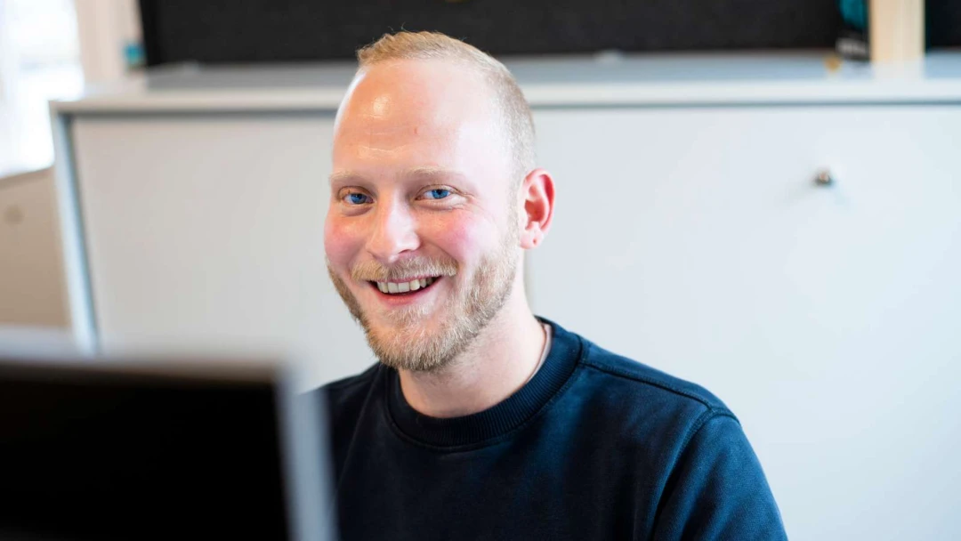 En leende kollega från HR Servicecenter framför en datorskärm.