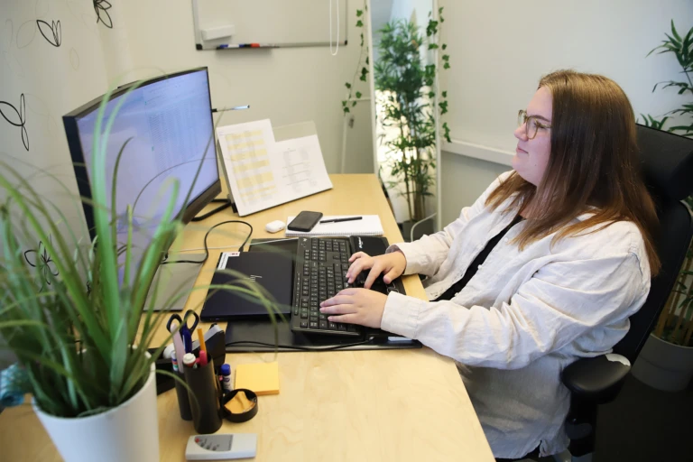 En kvinna sitter framför en dator vid ett skrivbord.