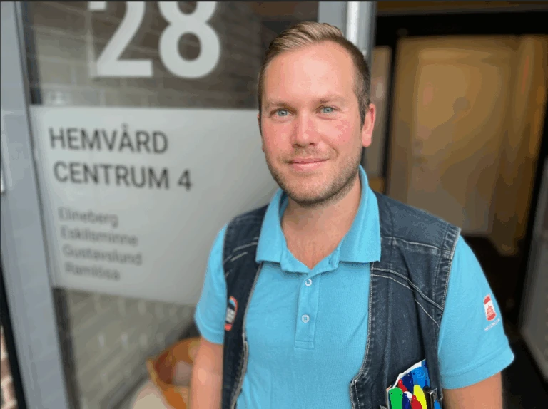 Man i ljusblå piké och jeansväst framför en glasdörr