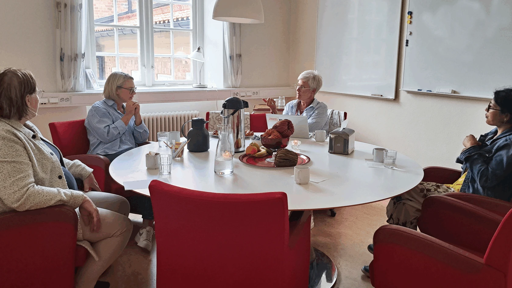 Fyra kvinnor sitter runt ett bord och har ett samtal.