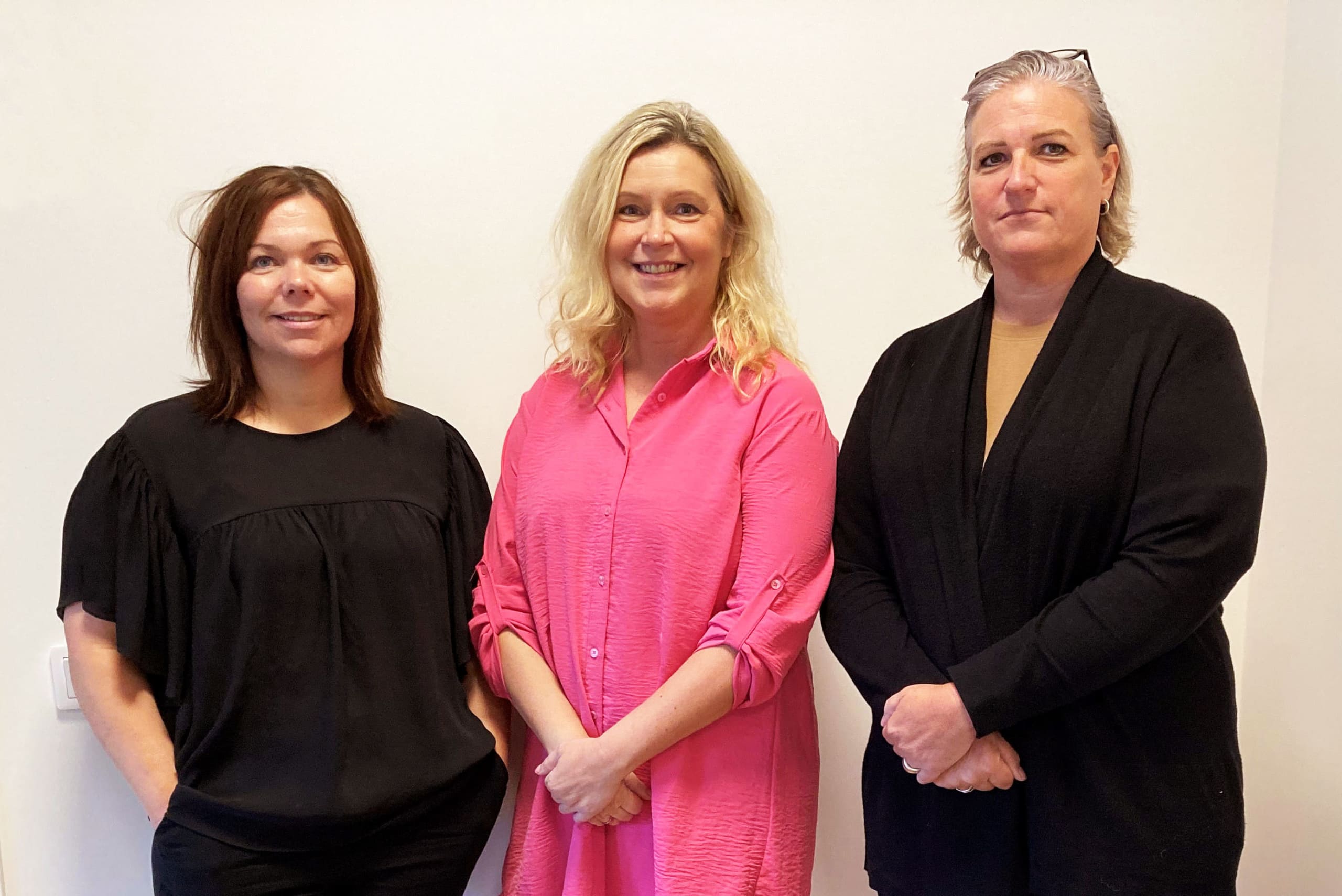 Tre kvinnor står på rad och tittar in i kameran