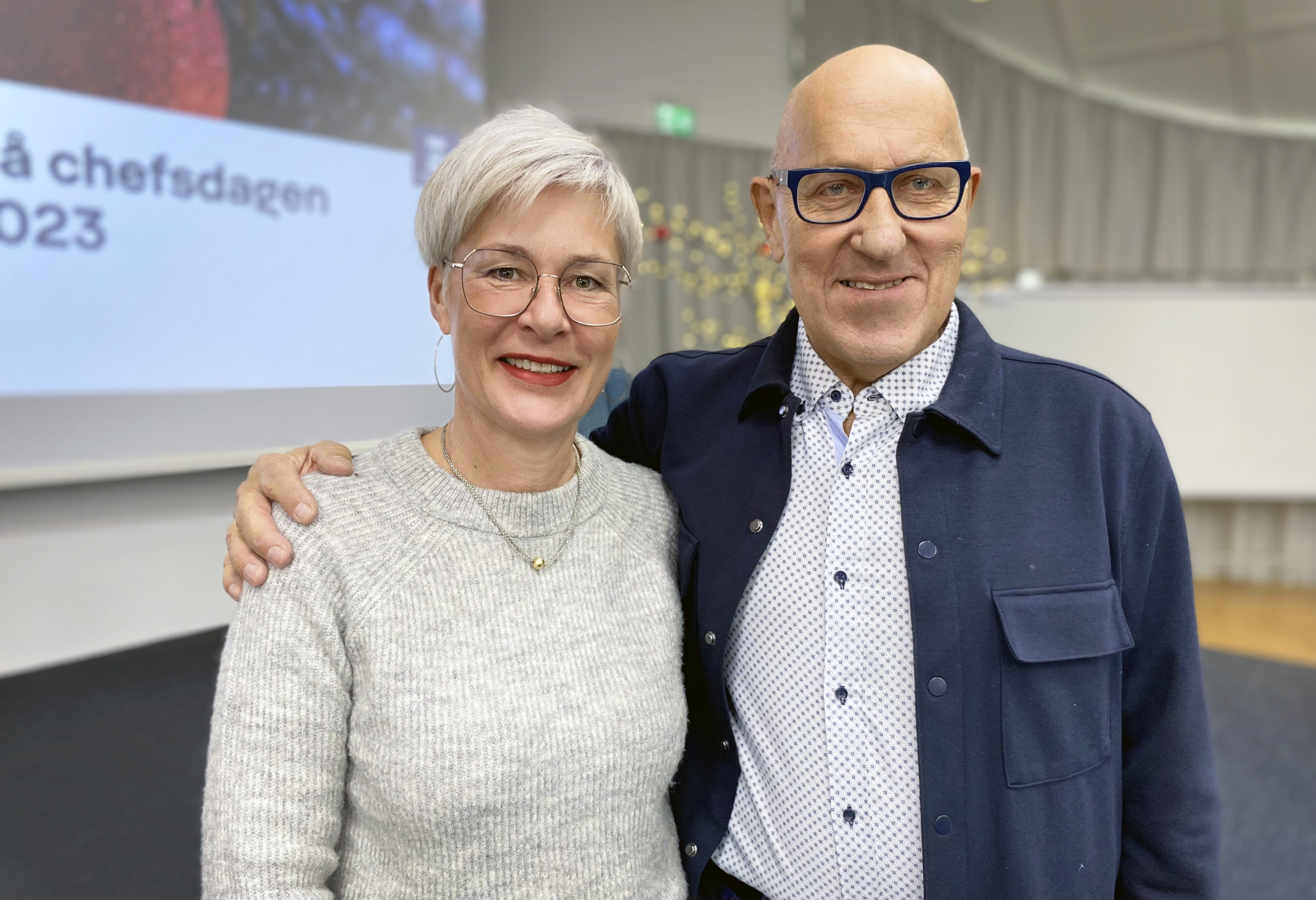 En kvinna och en man ler och tittar in i kameran.