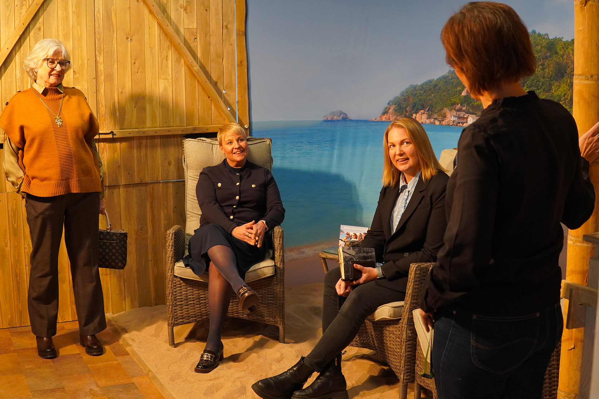 Fyra kvinnor pratar i ett rum med solvarma lampor.