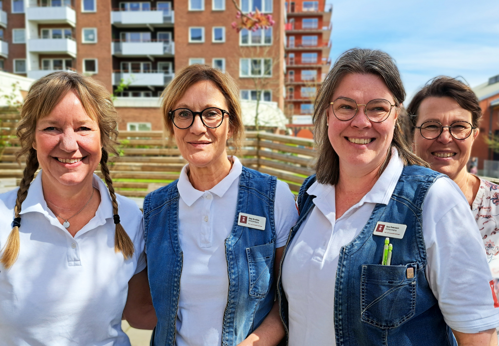 Fyra kvinnor står bredvid varandra på en uteplats.