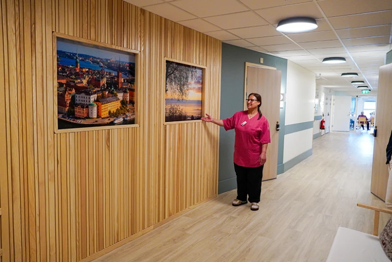 Ragnvallagården har renoverats. Korridorerna fått ljusa färger och akustikpaneler för behagligt ljud. Undersköterska Kafo visar de nya tavlorna med motiv från Helsingborg.