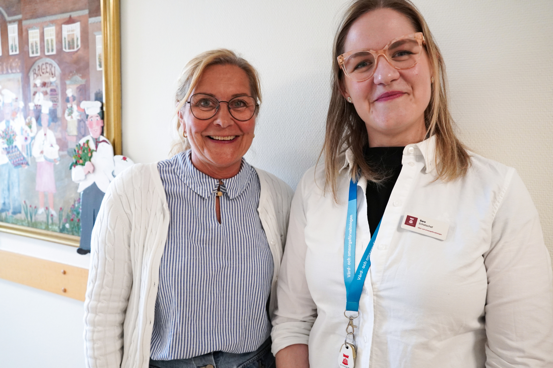 två personer ler och tittar in i kameran