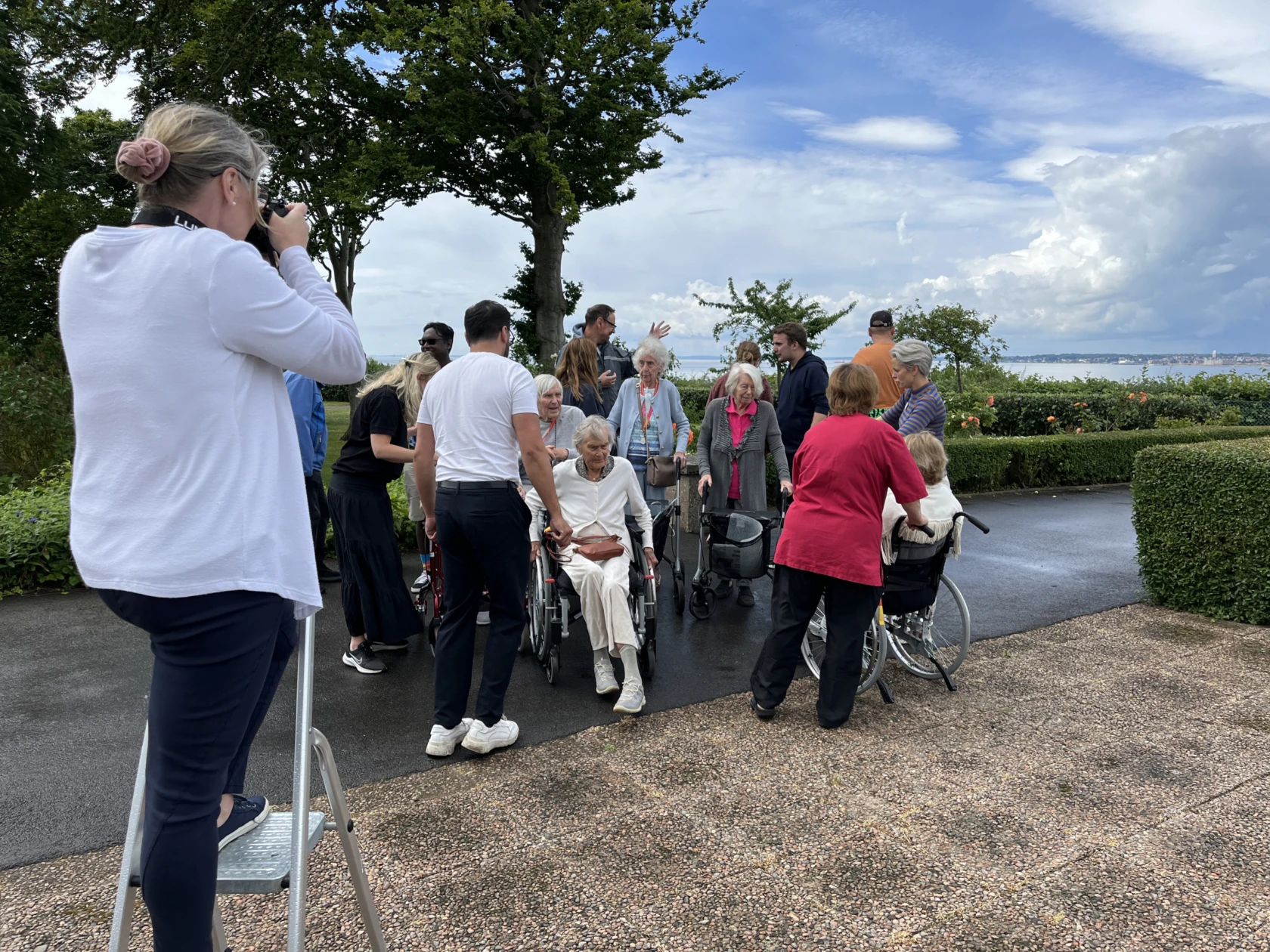 en fotograf står på stege med kamera framför en grupp människor