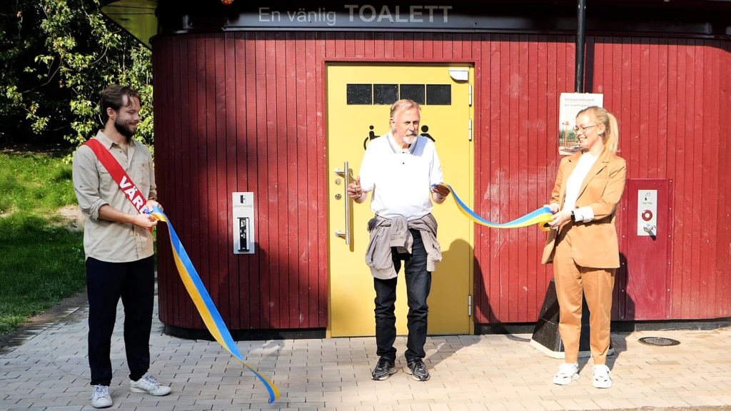 En man och en kvinna håller i ett bligult band som en man i mitten klipper av.