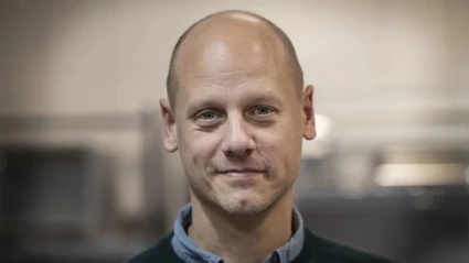 Ett ansikte tittar in i kameran och ler med stängd mun.