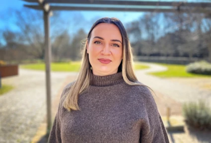 Ung kvinna ler och tittar in i kameran