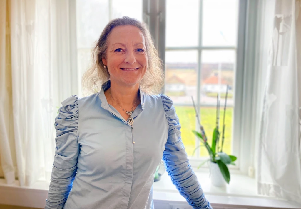 kvinna som ler och tittar in i kameran.