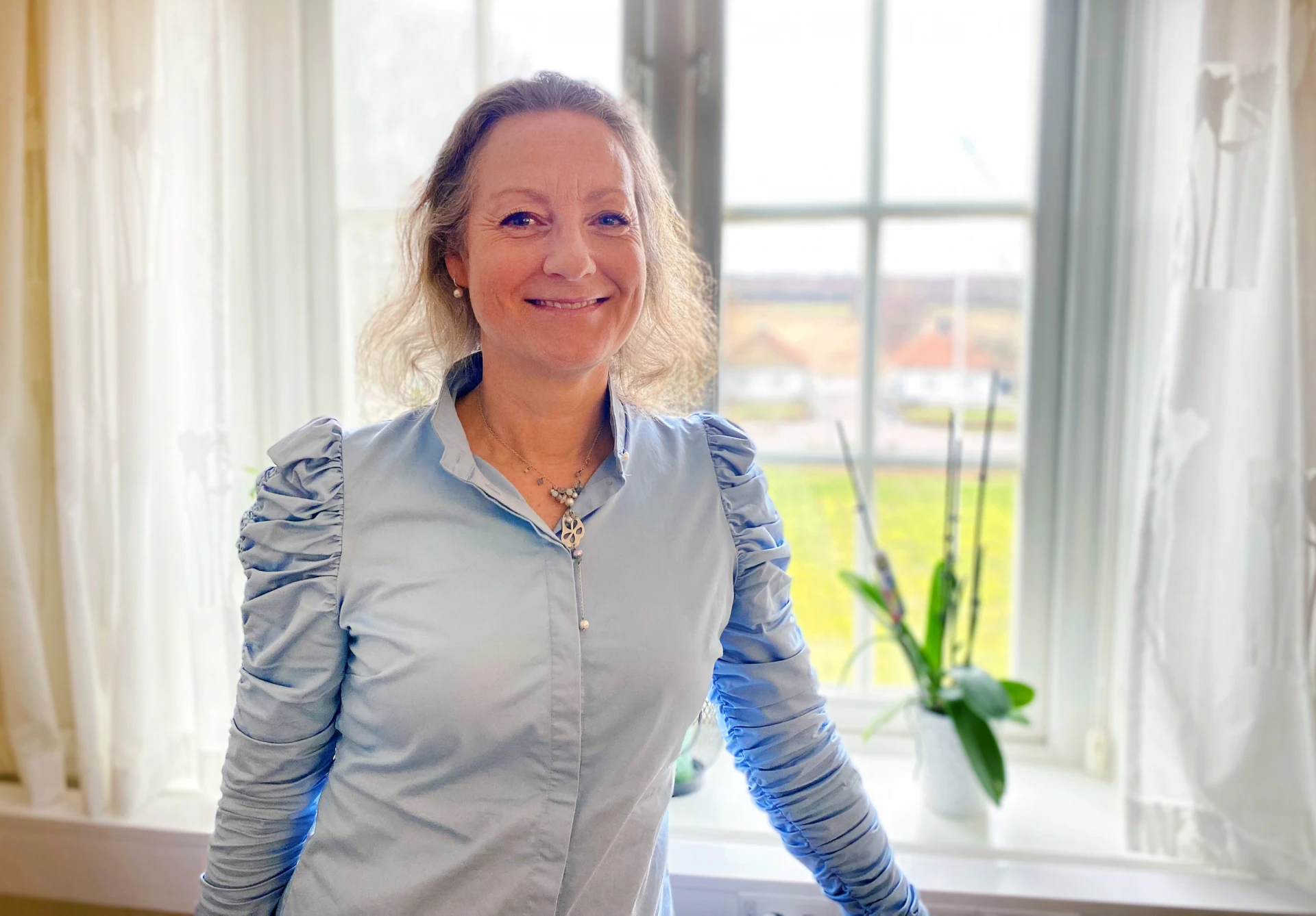 kvinna som ler och tittar in i kameran.