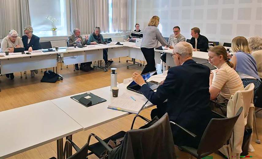 Män och kvinnor i olika åldrar sitter i ett stort konferensrum.