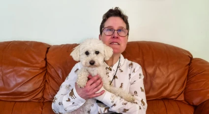 En person håller en hund i famnen.