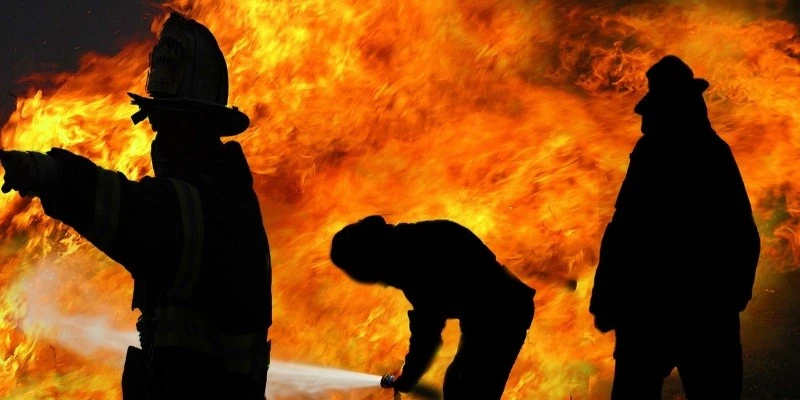 Tre personer står framför en brand.